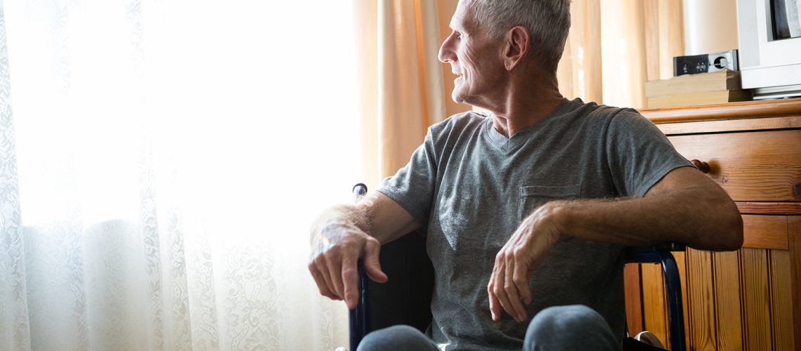 Thoughtful senior man looking away while sitting on wheelchair in nursing home
