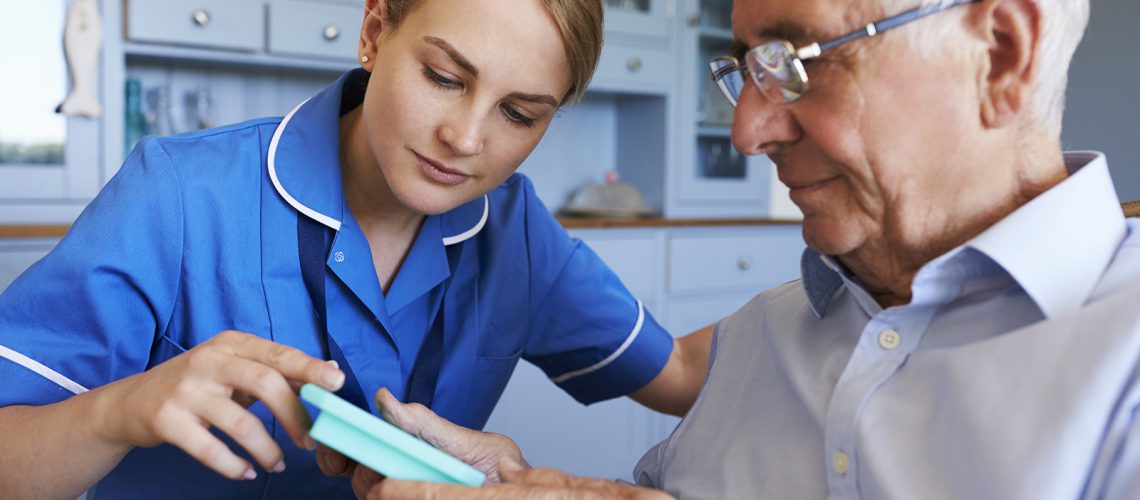 Nurse Helping Senior Man To Organize Medication On Home Visit
